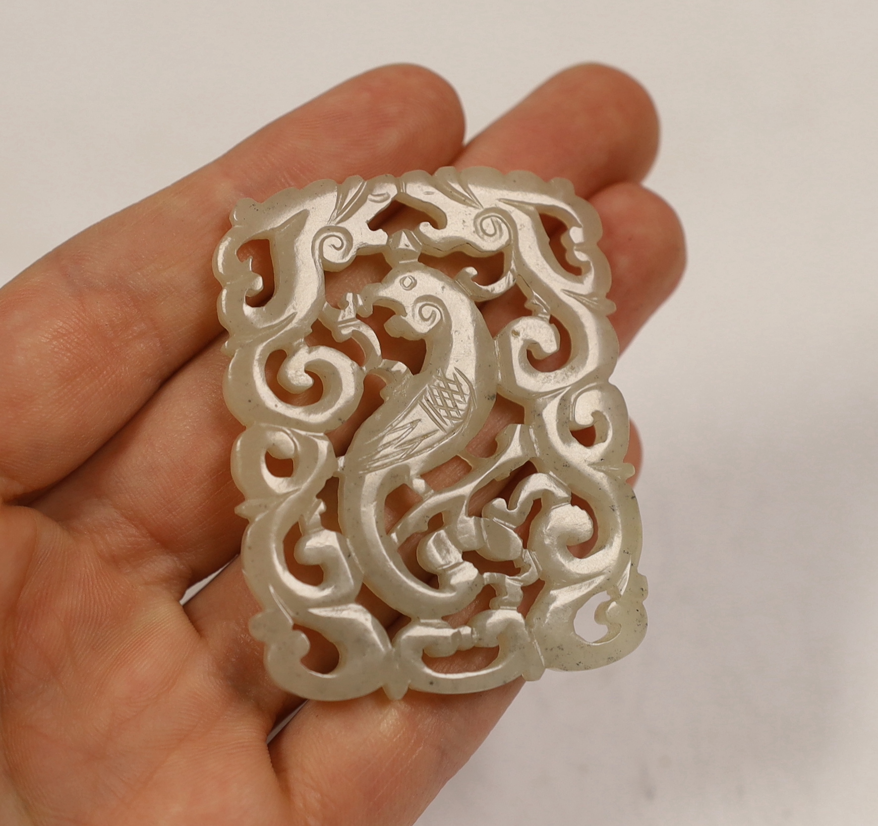 A Chinese jade ‘phoenix’ plaque, late 19th/early 20th century, 5.5 x 4.4cm on hardwood stand